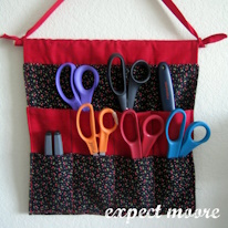 photo d'un rangement mural contenant cinq paires de ciseaux et deux autres outils