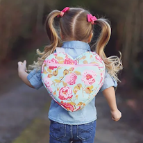 photo d'un enfant portent un sac à dos en forme de coeur à zipper rose