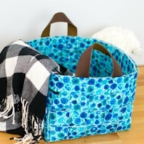 photo d'un panier en tissu bleu à fleurs contenant un plaid à carreaux