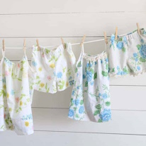 photo de deux pyjamas d'été à motifs floraux supendus à une corde à linge