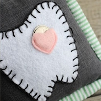 photo d'un petit coussin orné d'une dent en appliqué avec une mini poche pour une pièce