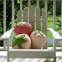 photo de trois coussins en forme de fraise sur un fauteuil d'extérieur