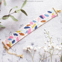 photo d'un bracelet en perles tissées orné de feuilles roses, jaunes et bleues