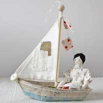 photo d'un bateau miniature dans lequel est assise une poupée
