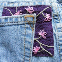 photo d'un jean réparé autour de la poche par un tacon brodé de fleurs