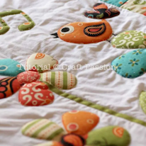 photo d'une couverture à motifs de fleurs et oiseaux en trapunto