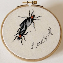 broderie de deux lucioles et des mots "Love bugs"